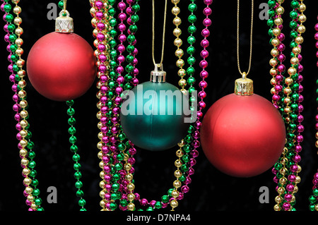 Rosso e verde di plastica baubles di Natale con perline colorate contro uno sfondo nero. Foto Stock