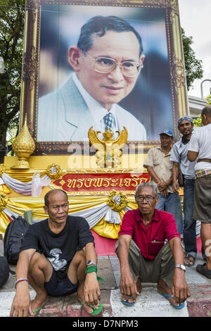 Bangkok, Tailandia. Maggio 11, 2013. Protesta degli agricoltori di sedersi di fronte un ritratto di Bhumibol Adulyadej, il Re della Thailandia. Diverse centinaia di piccola famiglia di scala gli agricoltori si sono accampate a ''Government House'' (l'ufficio del Primo Ministro a Bangkok alla pressione Primo Ministro tailandese Shinawatra Yingluck per offrire su di lei promette di migliorare la situazione della famiglia di agricoltori. Per il popolo€™s movimento per una società giusta (P-move) è un'organizzazione di rete il cui obiettivo è rafforzare la voce dei diversi ma cause relative al lavoro per portare la giustizia per gruppi emarginati in Thailandia, compresi i terreni ri Foto Stock