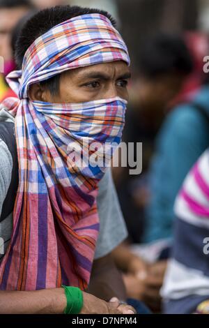 Bangkok, Tailandia. Maggio 11, 2013. Un manifestante con una bandana sul suo volto si trova nella strada di fronte la sede del governo. Diverse centinaia di piccola famiglia di scala gli agricoltori si sono accampate a ''Government House'' (l'ufficio del Primo Ministro a Bangkok alla pressione Primo Ministro tailandese Shinawatra Yingluck per offrire su di lei promette di migliorare la situazione della famiglia di agricoltori. Per il popolo€™s movimento per una società giusta (P-move) è un'organizzazione di rete il cui obiettivo è rafforzare la voce dei diversi ma cause relative al lavoro per portare la giustizia per gruppi emarginati in Thailandia, compresi i terreni a destra Foto Stock