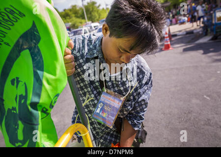 Bangkok, Tailandia. Maggio 11, 2013. Un agricoltore tailandese al cancello del P-Move encampment davanti al palazzo del governo. Diverse centinaia di piccola famiglia di scala gli agricoltori si sono accampate a ''Government House'' (l'ufficio del Primo Ministro a Bangkok alla pressione Primo Ministro tailandese Shinawatra Yingluck per offrire su di lei promette di migliorare la situazione della famiglia di agricoltori. Per il popolo€™s movimento per una società giusta (P-move) è un'organizzazione di rete il cui obiettivo è rafforzare la voce dei diversi ma cause relative al lavoro per portare la giustizia per gruppi emarginati in Thailandia, compresi i diritti alla terra per s Foto Stock