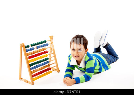 Piccolo ragazzo disteso sul pavimento con un abaco accanto a lui. Foto Stock