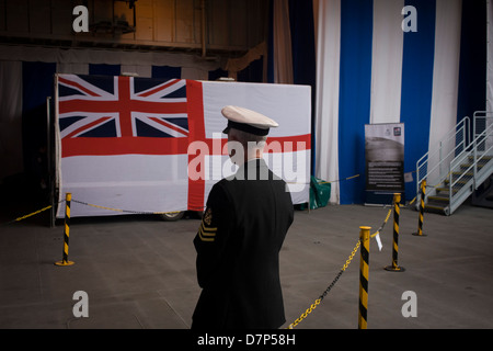 Un Chief Petty Officer in prossimità della Marina di alfiere bandiera sulla hangar deck durante una gita con il pubblico in generale a bordo della Royal Navy la portaerei HMS illustri nel corso di un pubblico aperto-giorno di Greenwich. Illustri ancorato sul fiume Tamigi, consentendo al contribuente di pubblico tour i suoi mazzi di carte prima del suo imminente decommisioning. Il personale della Marina ci ha aiutato con il PR evento oltre il fine settimana di maggio, storicamente la casa di Gran Bretagna flotta navale. Foto Stock