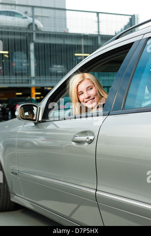 Donna indietro la sua auto in un parcheggio livello o parcheggio deck Foto Stock