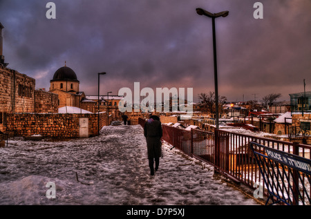 Ebrea ortodossa uomo a camminare nella neve percorso sui tetti di Gerusalemme la città vecchia Foto Stock