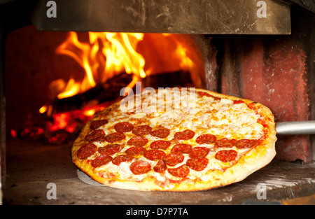 Una salsiccia per pizza pizza cuoce in forno a legna per la pizza. Foto Stock