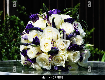 Brides disposizione di fiori viola e rose bianche sul giorno di nozze Foto Stock