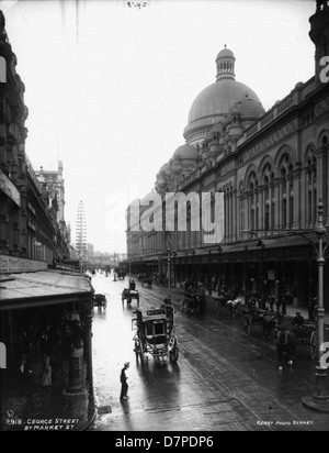 Questa foto storica di George Street di Sydney mostra un autobus trainato da cavalli che passa per il Queen Victoria Market, con strade bagnate e un tendalino visibile. L'immagine, catturata vicino al Powerhouse Museum, mostra il paesaggio urbano di Sydney all'inizio del XX secolo. Foto Stock