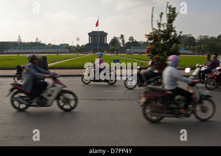 Paesaggio urbano orizzontale di ciclomotori e moto la guida ha superato il Mausoleo di Ho Chi Minh nel centro di Hanoi in una giornata di sole. Foto Stock