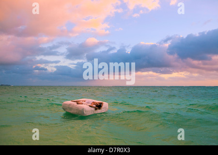 La donna nel suo letto alla deriva in mare Foto Stock