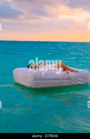 La donna nel suo letto alla deriva in mare Foto Stock