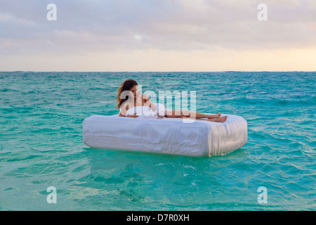 La donna nel suo letto alla deriva in mare Foto Stock