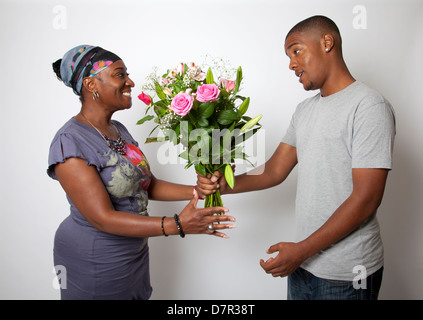 Cresciuto figlio dando la sua mamma fiori Foto Stock