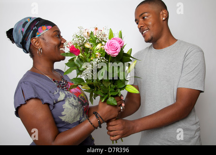 Cresciuto figlio dando la sua mamma fiori Foto Stock