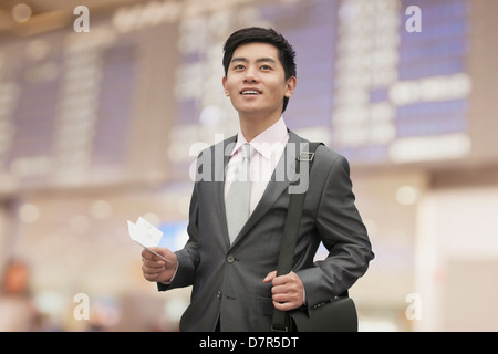 Imprenditore giovane azienda biglietto presso l'aeroporto, Pechino, Cina Foto Stock