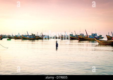 Un pescatore casting net presso la spiaggia di Mui Ne, Vietnam Foto Stock