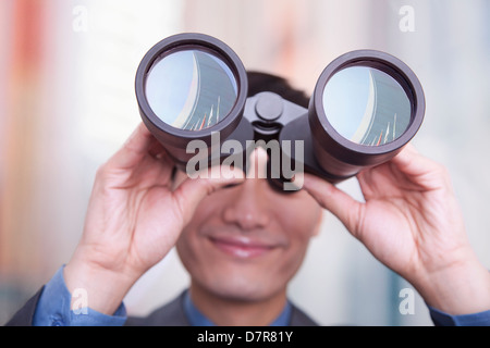 Giovane imprenditore cerca attraverso il binocolo, Pechino Foto Stock