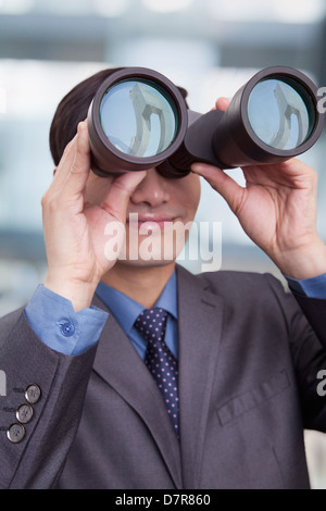 Giovane imprenditore cerca attraverso il binocolo, Pechino Foto Stock