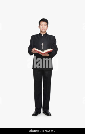 Giovane sacerdote in piedi con la Bibbia Foto Stock