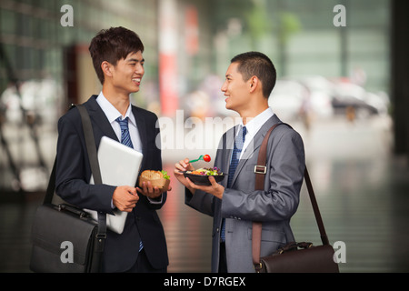 Due giovani imprenditori parlando e avente un pranzo all'aperto Foto Stock