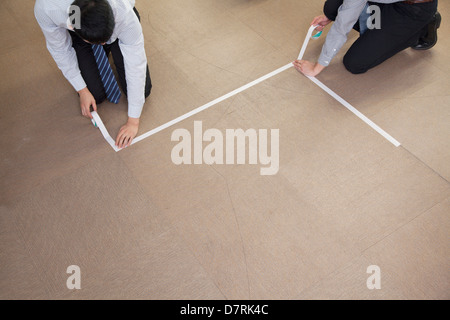 Due giovani imprenditori la nastratura fino al pavimento in ufficio Foto Stock