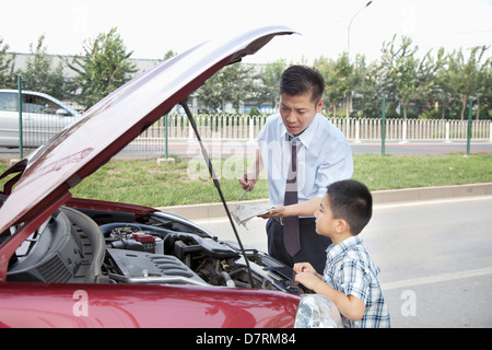 Padre e Figlio di controllare il livello di olio sulla loro auto Foto Stock