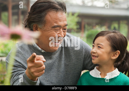 Nonno e nipote guardando il fiore nel giardino Foto Stock