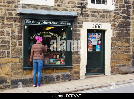 Pately Bridge, North Yorkshire, Inghilterra. Ragazza cerca nella finestra del più antico negozio di dolci in Inghilterra, fondata nel 1827. Foto Stock