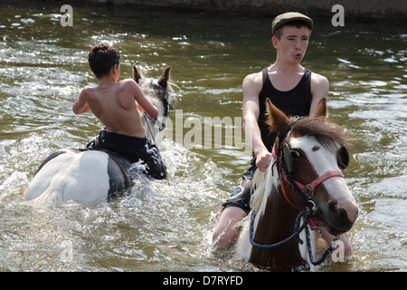 Ragazzi a cavallo nel fiume Eden durante la fiera a Appleby, un incontro annuale di zingari e nomadi europee in Cumbria. Foto Stock