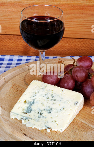 Il bleu d'Auvergne formaggio, vino rosso e uva rossa su una tavola di legno di formaggi. Foto Stock