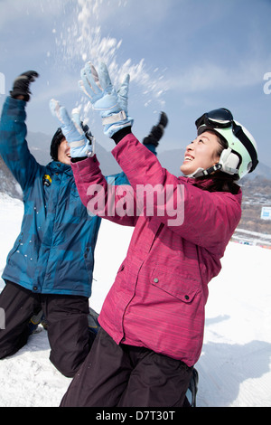 Giovane uomo e donna giocare nella neve nella stazione sciistica Foto Stock