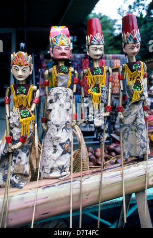 Quattro colorato scolpiti a mano e dipinte a mano e legno-asta marionette sono schierate per la vendita in un negozio sull'isola di Java in Indonesia, sud-est asiatico. Foto Stock