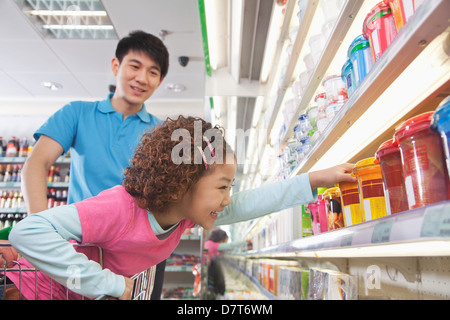 Bambina per raggiungere il cibo in un supermercato Foto Stock