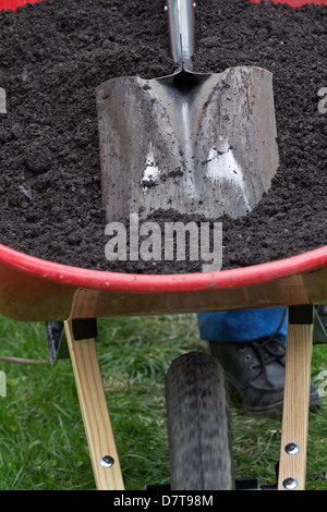 La primavera lavora in giardino con un carriola con terreno pieno e una pala in primo piano dal formato verticale sopraelevato negli Stati Uniti ad alta risoluzione Foto Stock