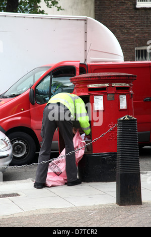 British portalettere raccogliere la posta da una cassetta delle lettere, in Paddington, London, Maggio 2013 Foto Stock