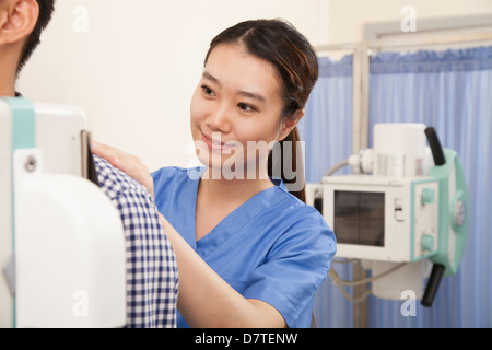 Medico donna esame paziente di sesso maschile di metà sezione con macchina a raggi X Foto Stock