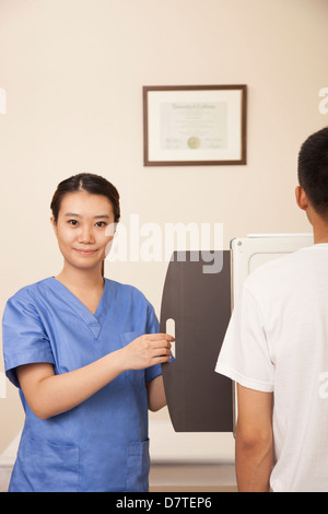 Medico donna esame paziente di sesso maschile di metà sezione con macchina a raggi X Foto Stock