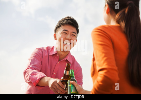 Gli amici la tostatura a vicenda su un tetto Foto Stock