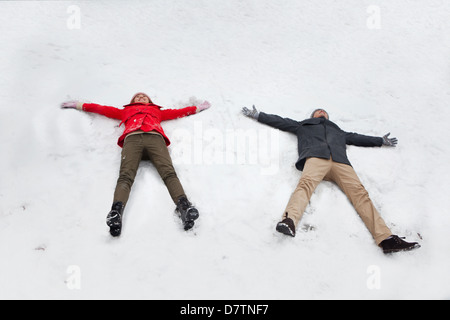 Coppia giovane posa in snow making angeli di neve Foto Stock