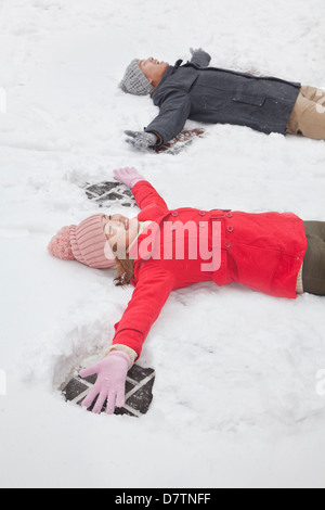 Coppia giovane posa in snow making angeli di neve Foto Stock