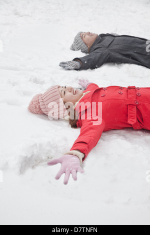 Coppia giovane posa in snow making angeli di neve Foto Stock