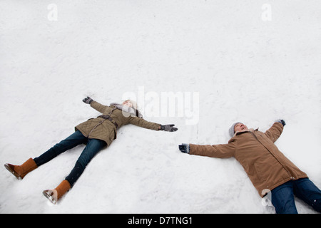 Coppia giovane posa in snow making angeli di neve Foto Stock