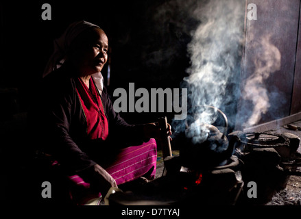 Donna della tribù Palaung per la cottura sul fuoco aperto nella sua casa di villaggio nei pressi di Kengtung (Kyaingtong), Stato Shan, Birmania Foto Stock