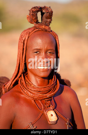Himba donna dentro una dimora di fango hut indossando abiti e gioielli e coperto di Otjize, Regione di Kunene, Kaokoland, Namibia Foto Stock