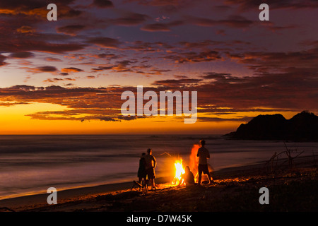 Persone con driftwood fire al tramonto su Playa Guiones beach, Nosara, Nicoya peninsula, provincia di Guanacaste, Costa Rica Foto Stock