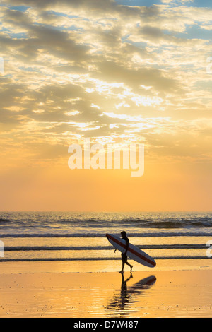 Surfer con lungo bordo al tramonto sulla popolare Playa Guiones surf beach, Nosara, Nicoya peninsula, provincia di Guanacaste, Costa Rica Foto Stock