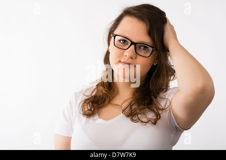 Un giovane brunette teenage ragazza caucasica indossando occhiali confuso interessati di graffiare la sua testa Foto Stock