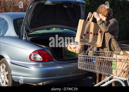 Giorno nella Vita, donna shopping caricamento in auto con ri utilizzare sacchetti, dopo lo shopping a Tesco nel Regno Unito Foto Stock