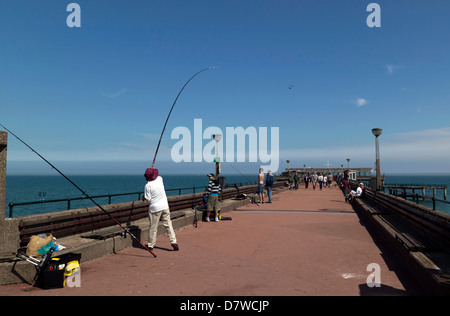 Fisherman casting off sul molo di trattativa, trattare, Kent. Foto Stock