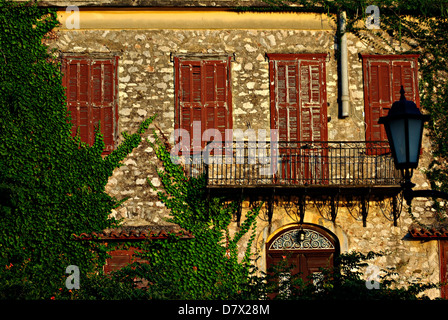 Trascurato vecchia casa rustico con balcone ed edera sul muro al sole del pomeriggio. Foto Stock