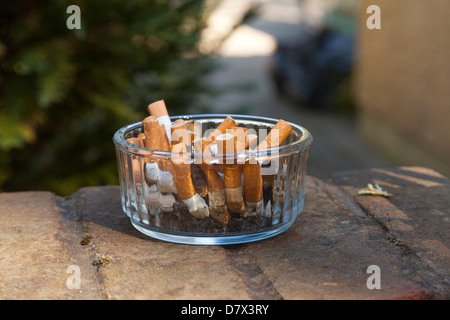 Mozziconi di sigarette nella ciotola posacenere Foto Stock